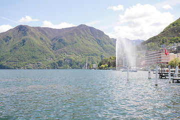 Image showing Mountainside villas and appartments at lake with waterfountain i