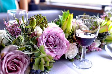 Image showing Glass of wine placed beside freshly arranged flowers
