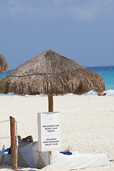 Image showing Straw umbrella with sign infront 