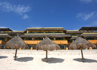 Image showing Three grass umbrellas on a resort beach 