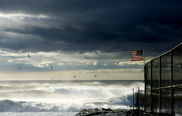 Image showing American flag on a fence along the beach  