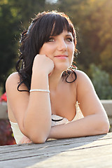 Image showing Girl in the wedding dress sitting on the bench