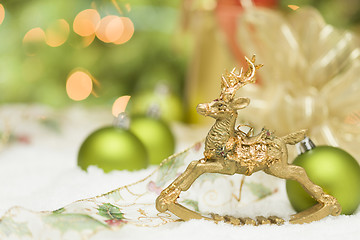 Image showing Golden Christmas Reindeer Ornament Among Snow, Bulbs and Ribbon