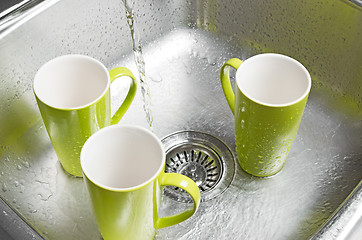 Image showing Washing green cups in the kitchen sink