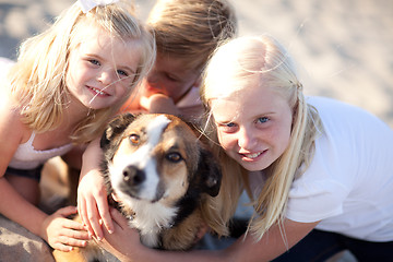 Image showing Cute Sisters and Brother Playing with Dog