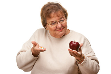 Image showing Confused Senior Woman Holding Apple and Vitamins