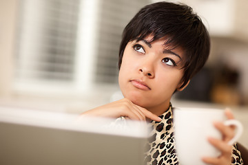 Image showing Pretty Mixed Race Woman Holding Cup Using Laptop