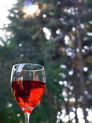 Image showing Glass of red wine outdoors with lens flare