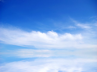 Image showing white fluffy clouds with rainbow in the blue sky