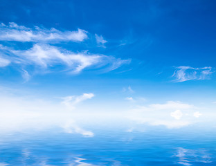 Image showing white fluffy clouds with rainbow in the blue sky