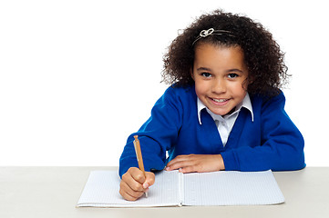 Image showing Cute primary kid writing her assignment