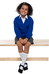 Image showing Pretty school girl seated comfortably on a bench