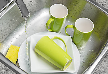 Image showing Washing green cups and plates in the kitchen sink