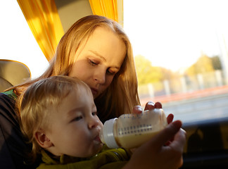 Image showing Mother is feeding her kid in the bus.