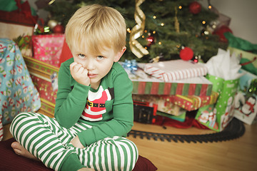 Image showing Young Grumpy Boy Sitting Near Christmas Tree