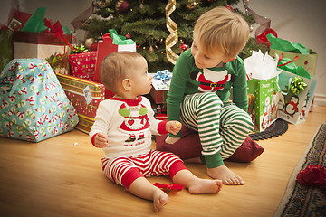 Image showing Baby and Young Boy Enjoying Christmas Morning Near The Tree