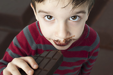 Image showing Smiling little boy eating chocolate