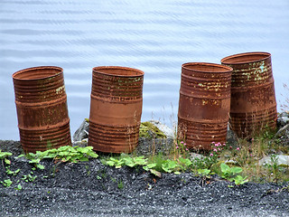 Image showing Old rusty waste barrels by the sea