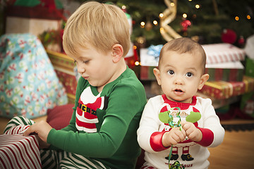 Image showing Baby and Young Boy Enjoying Christmas Morning Near The Tree