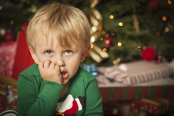 Image showing Young Grumpy Boy Sitting Near Christmas Tree