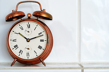 Image showing vintage copper alarm clock on the mantelshelf 