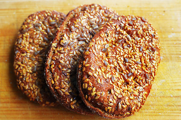 Image showing three sandwich buns with sesame seeds on cutting board 