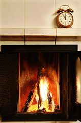 Image showing fireplace and  old-fashioned copper alarm clock on the mantelshe