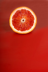 Image showing Juicy half of a blood orange on a red background