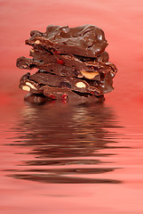 Image showing Chocolate cashew and dried cherry bark in water on a red backgro