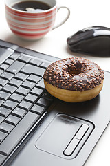 Image showing break in the  office . doughnut on laptop keyboard