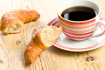 Image showing breaking croissant with coffee