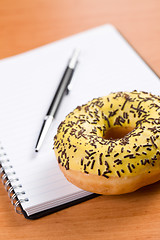 Image showing sweet doughnut and spiral notebook