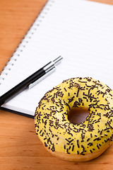 Image showing sweet doughnut and spiral notebook