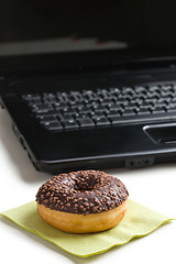 Image showing break in the  office . doughnut on laptop keyboard