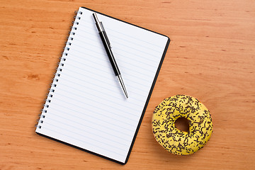 Image showing sweet doughnut and spiral notebook