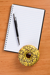 Image showing sweet doughnut and spiral notebook