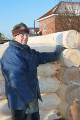 Image showing Carpenter produces log-house