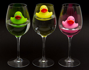 Image showing Green, yellow and pink rubber ducks in wineglasses