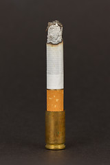 Image showing Burning cigarette in an old tin ashtray