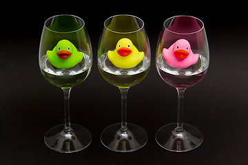 Image showing Green, yellow and pink rubber ducks in wineglasses