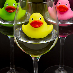 Image showing Green, yellow and pink rubber ducks in wineglasses