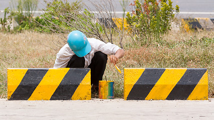 Image showing Man painting roadworks barriers on a road in Vietnam