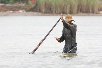 Image showing A vietnamese fisherman is searching for snakes and shells in the