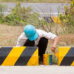 Image showing Man painting roadworks barriers on a road in Vietnam