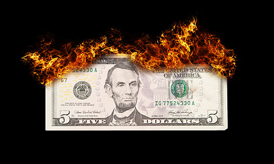 Image showing Burning five dollar bill symbolizing careless money management