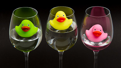 Image showing Green, yellow and pink rubber ducks in wineglasses