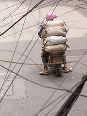 Image showing Typical Hanoi; Man with heavy load on scooter drives through Han