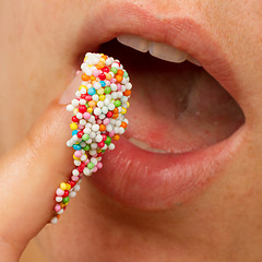 Image showing Woman lips and finger with multicolored pearls 