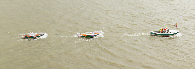Image showing Motorboat dragging some rowing-boats