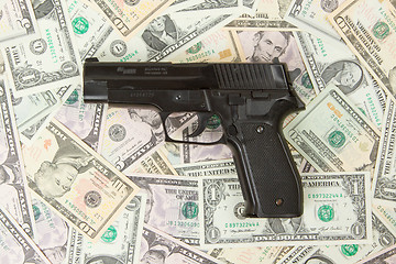 Image showing Black gun isolated on a heap of money